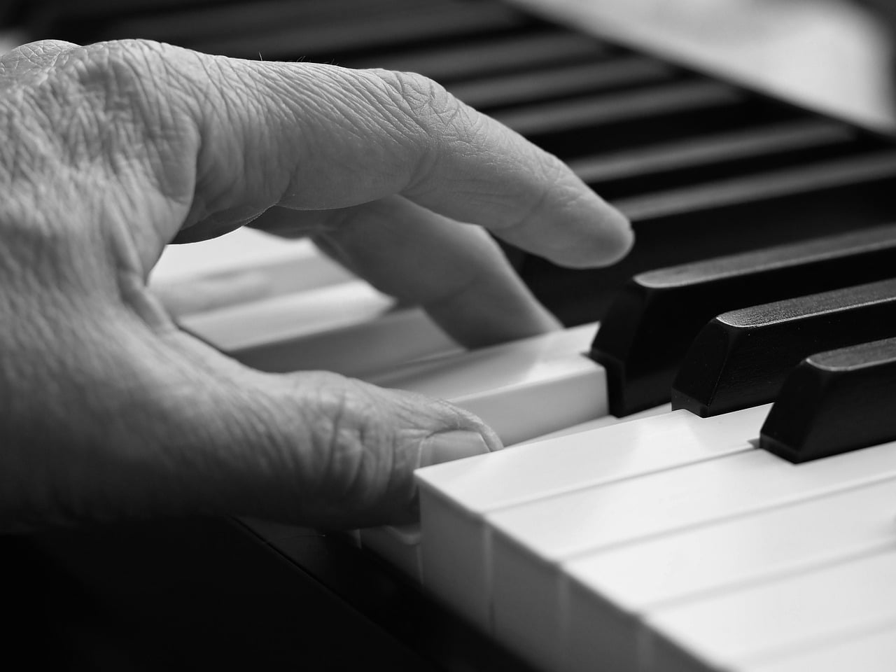 Black and white photograph of a hand playing keyboard keys